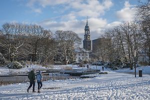 Zwei Spaziergänger laufen durch den mit Schnee bedeckten Park